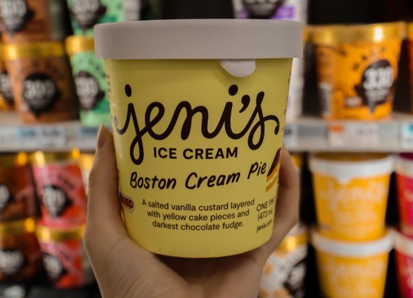 A yellow and white tub of ice cream with the words, “Jeni’s Ice Cream Boston Cream Pie” in black cursive lettering.