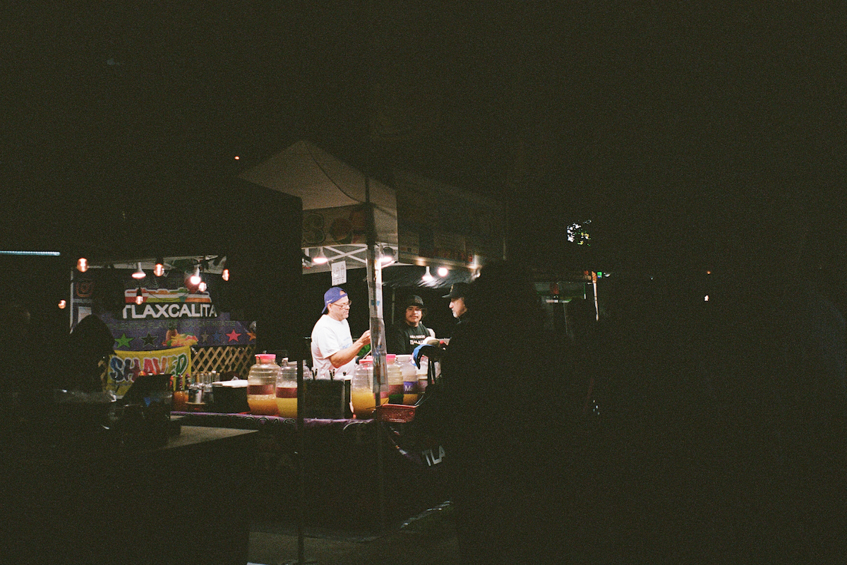 A photo of a street vendor at night, only two chefs and their tent lit up.