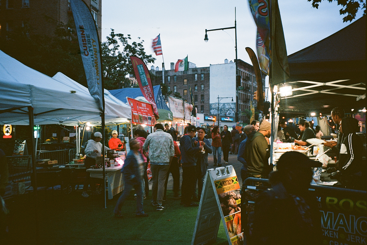 People walking around a street with many food vendors.