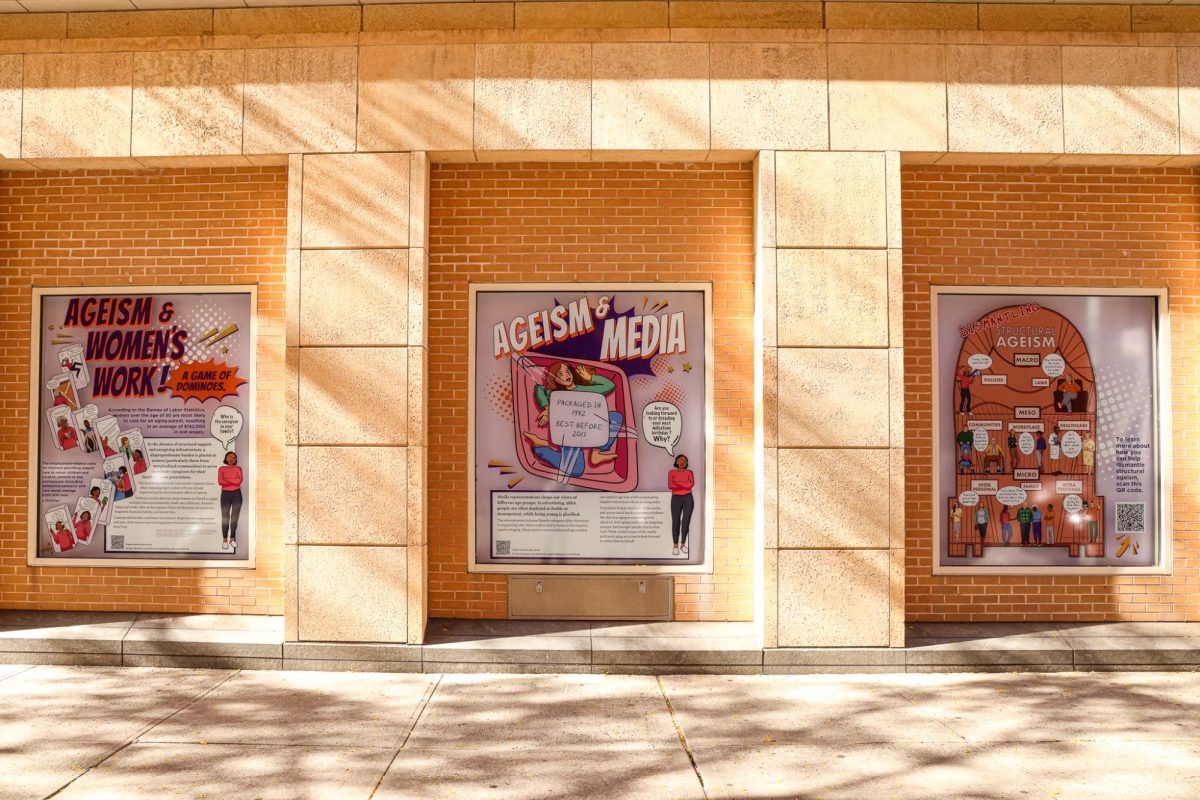 A shot of the side of a building. Various posters are hung on the wall with the word “Ageism” written on each.