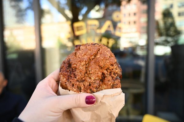 A hand holding a cookie in front of a bakery display window that says “LIBRAE BAKERY". 