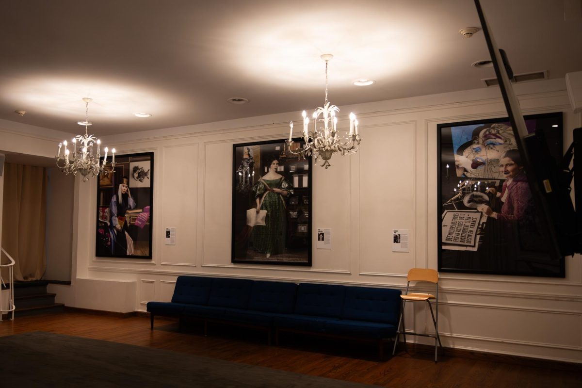 A room with three framed prints hanging above a blue sofa, lit by chandeliers.