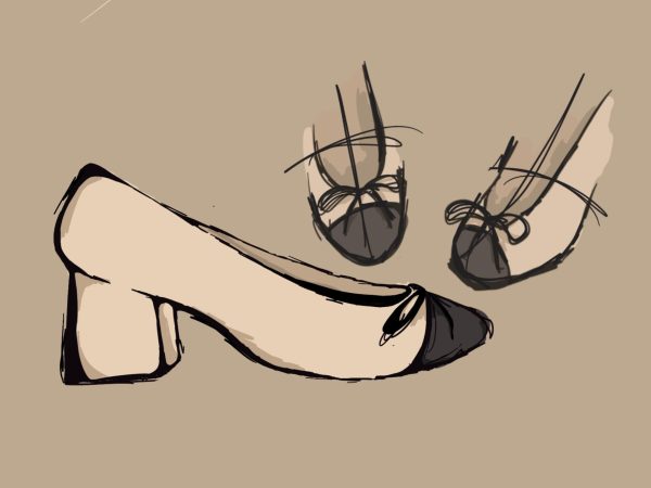 A ballerina shoe with a small heel. The tip of the shoe is black and the rest of the shoe is beige. There is a bow on the front of the shoe. 