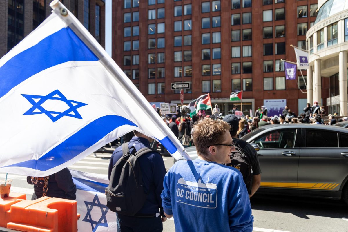 A group of protesters gathered around Stern School of Business, holding Israeli and Palestinian flags.