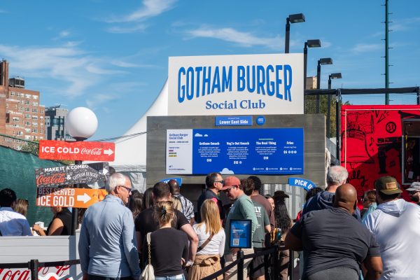 People standing in line for a restaurant called “GOTHAM BURGER Social Club.”