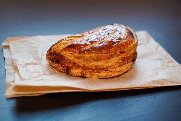 A filled puff pastry on a brown paper bag laid on a table.