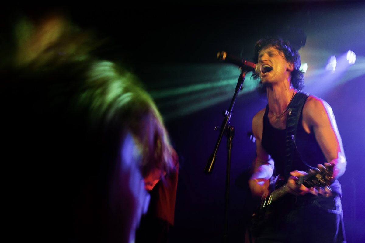 A man singing into a microphone and playing the guitar.