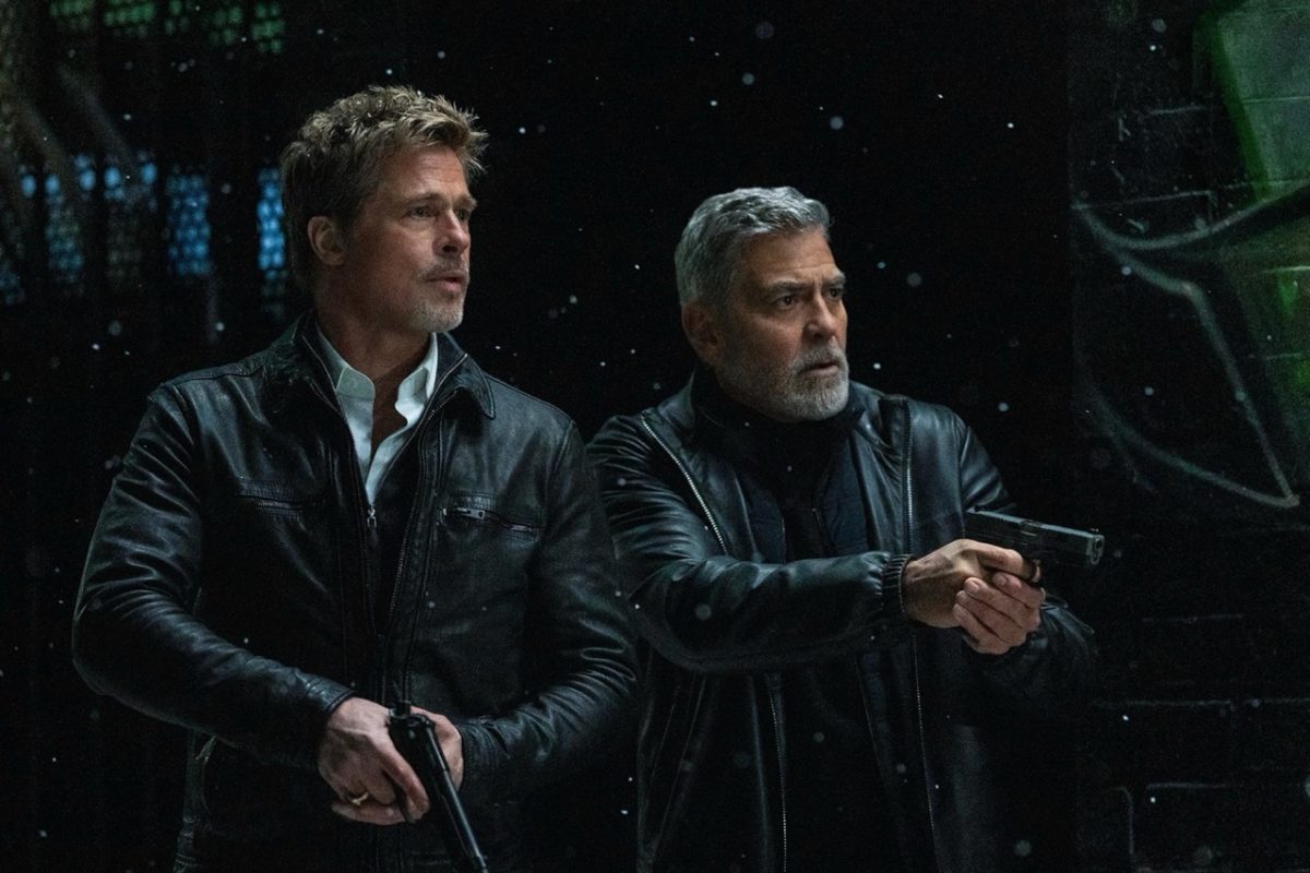 Two men in leather jackets hold guns while it is snowing.