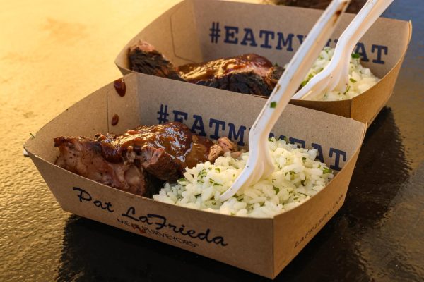 Two cardboard dishes with meat and rice sit on a table.