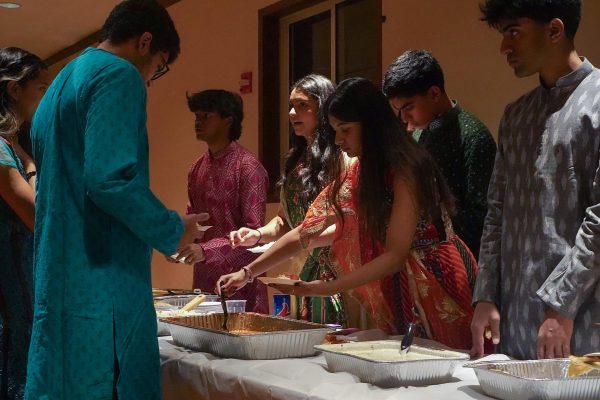 People serve food to people who are waiting in line.