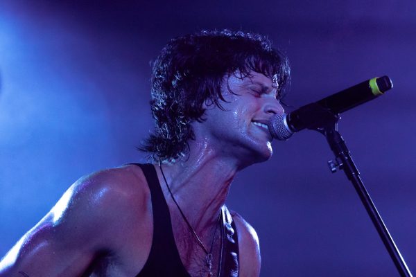 A man passionately singing into a microphone with his eyes closed.