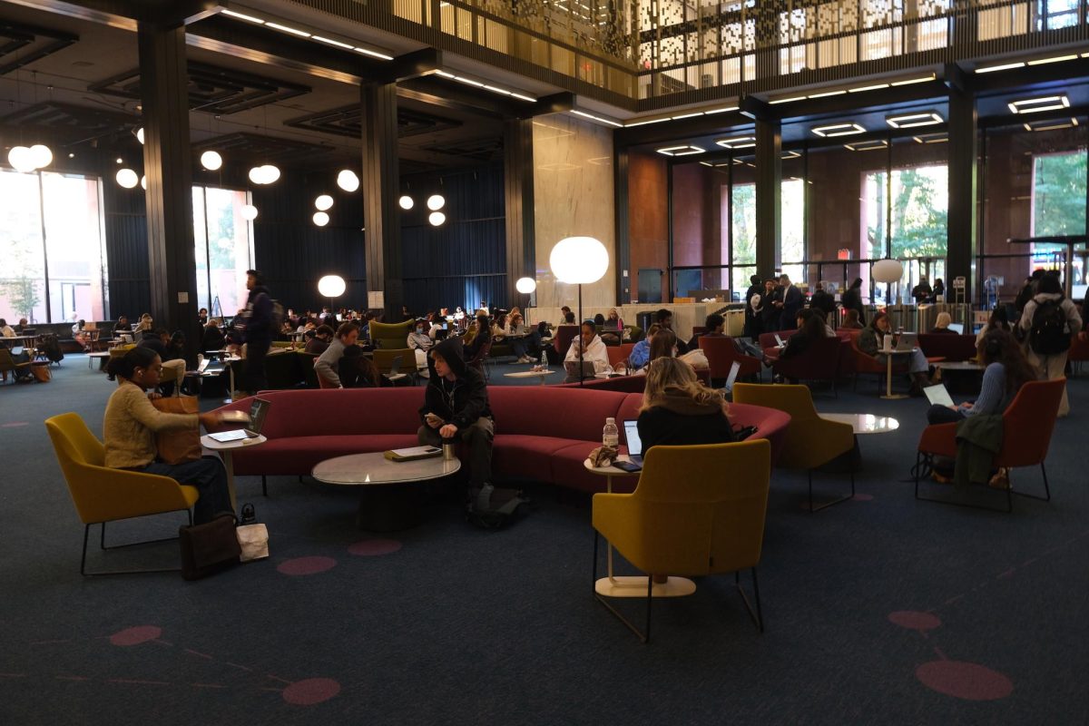 A spacious study area in a library with students working on laptops.