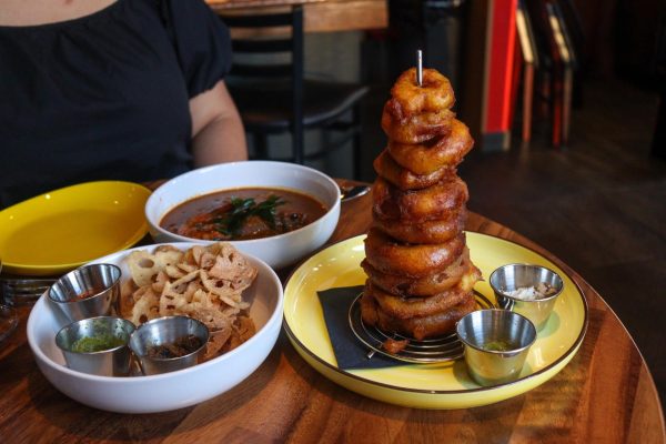 A close-up shot of a meal including onion rings, fried lotus root, and red soup.