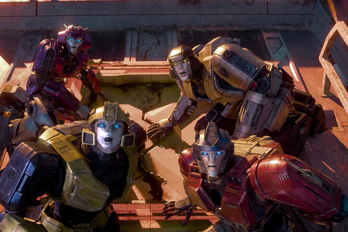 A group of four robots in metallic purple, yellow, and red colors, surrounded with sci-fi settings. They are gathered together, looking upwards with surprise.