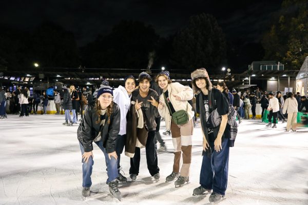 A group of smiling students pose for a photo in an ice rink.