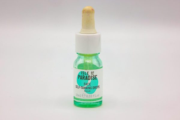 A green dropper bottle with the words “Isle of Paradise Face Self-Tanning Drops” printed on a white label.