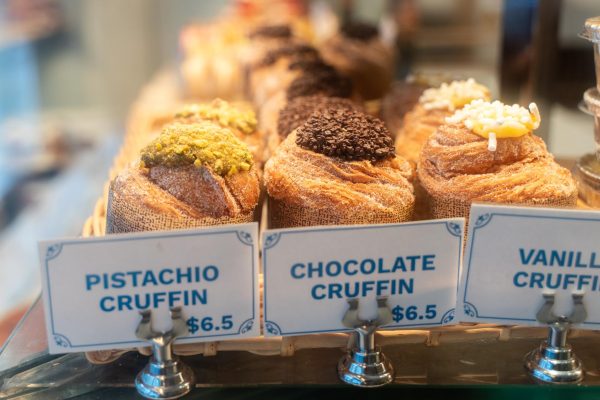 Pastries with different toppings behind a glass. In front of them, there are signs that read “Pistachio Cruffin $6.5” and “Chocolate Cruffin $6.5.”