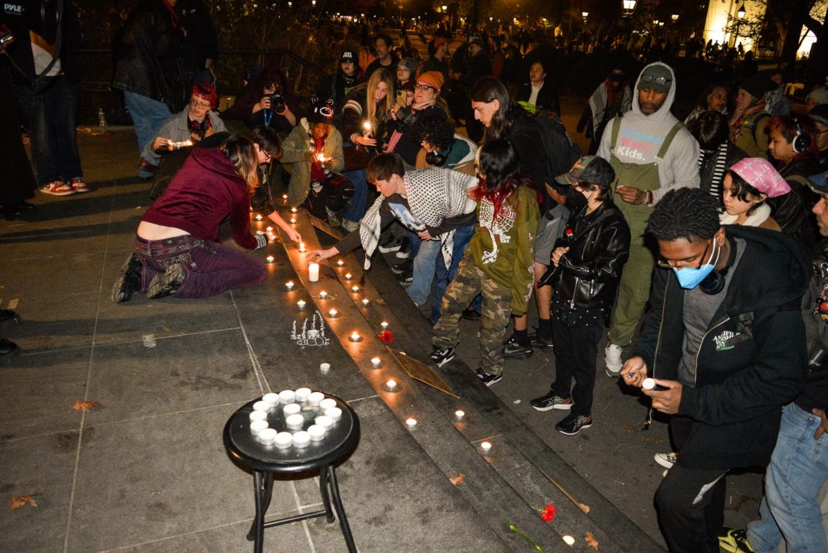 People stand in front steps lined with candles, while others light them.