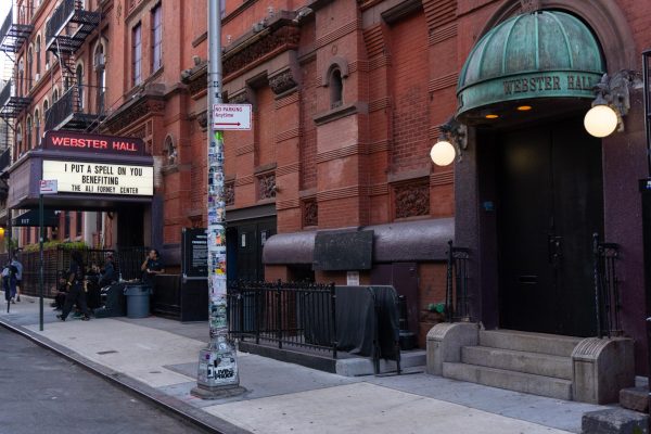 The exterior of a building with a green awning and a light-up sign that reads “Webster Hall.”