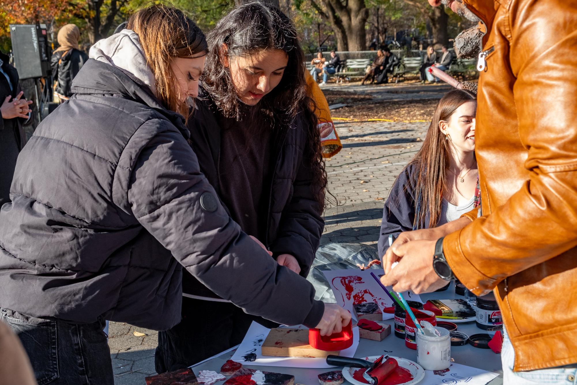 Two people doing block print art at a table outside.