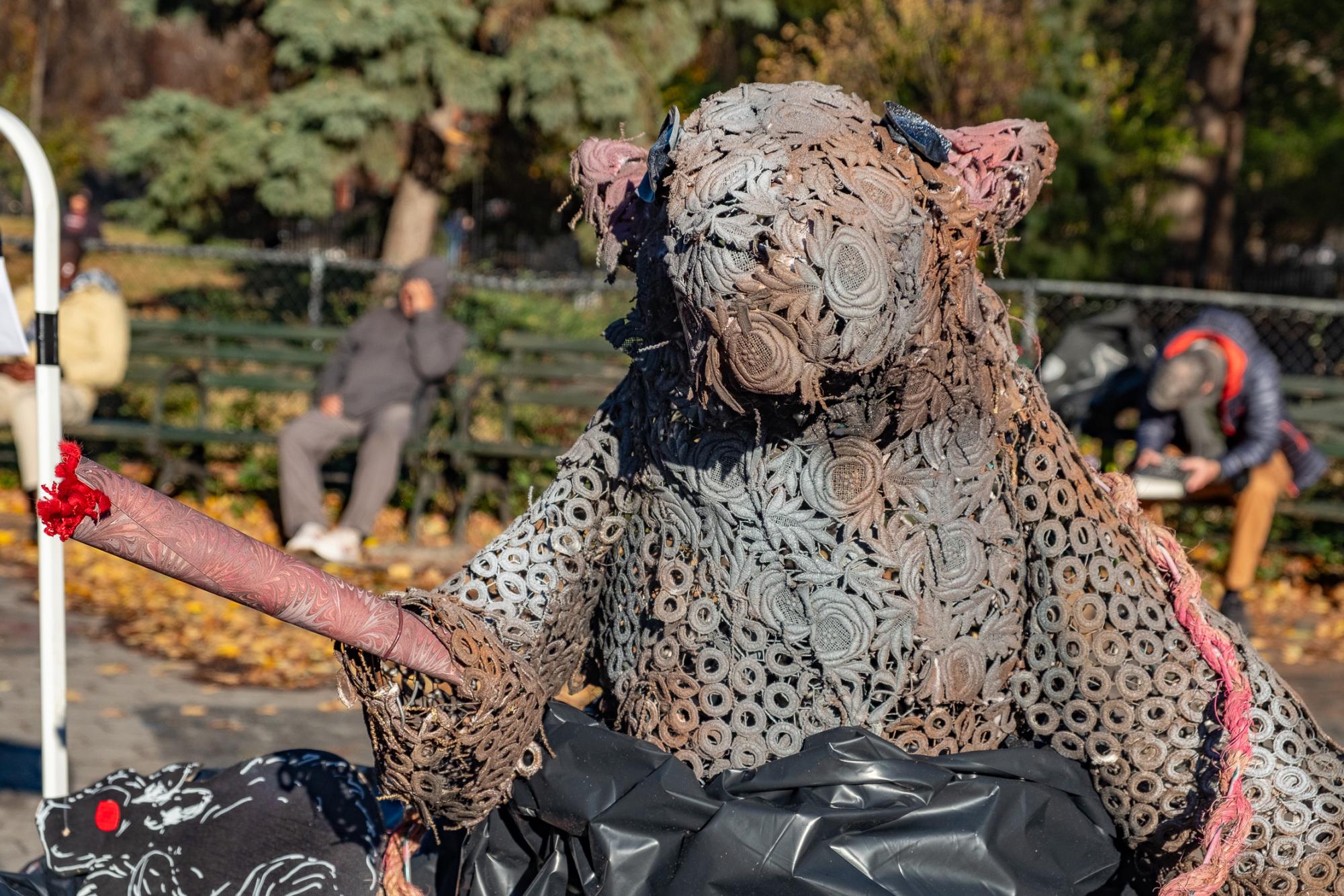 A large statue made out of fabric and metal materials depicting a gray rat holding a blunt.