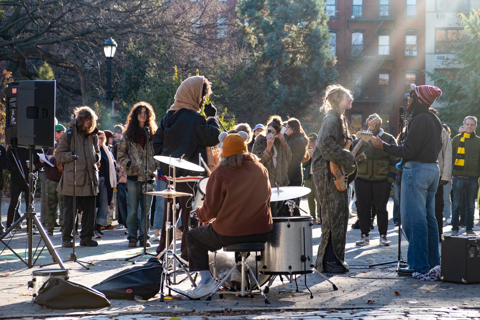 A band performing in front of a crowd outside in a park.