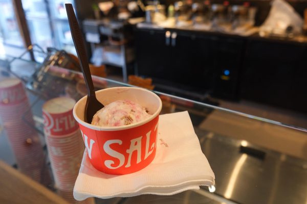 A cup of white-and-pink ice cream in an orange cup sits on a counter.