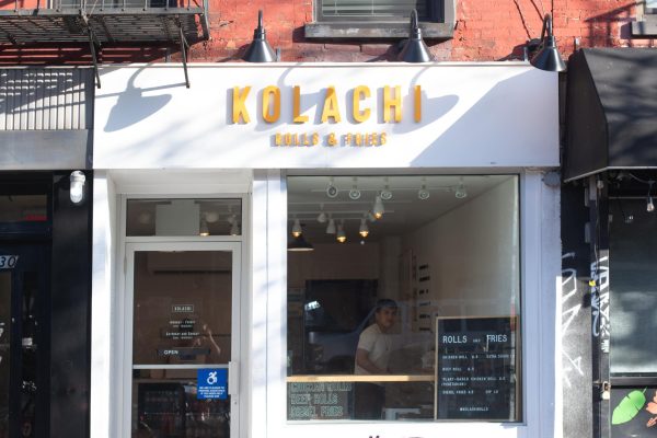 A white building with the name “KOLACHI” written in bright yellow letters. Underneath, it says “ROLLS AND FRIES” in the same yellow.