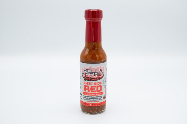 A bottle of red hot sauce with a silver and red label that reads “Hell’s Kitchen Hot Sauce, West Side Red” with a red drawing of the New York City skyline.