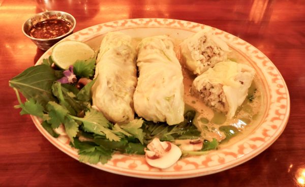 Cabbage rolls stuffed with turkey, sitting on a plate with broth and a celery garnish