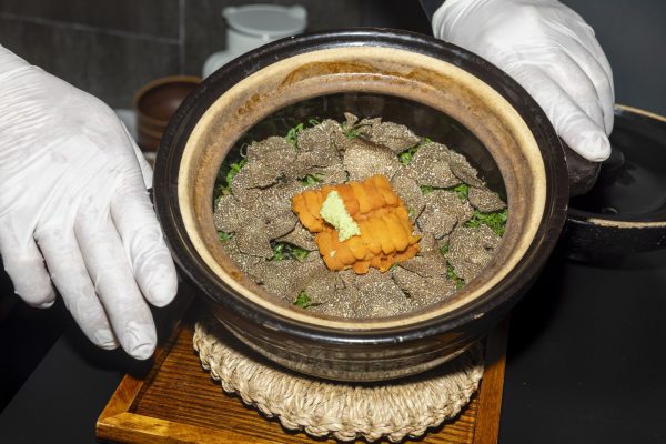 A plate with an orange food laying on top of truffles, with lettuce as the base.