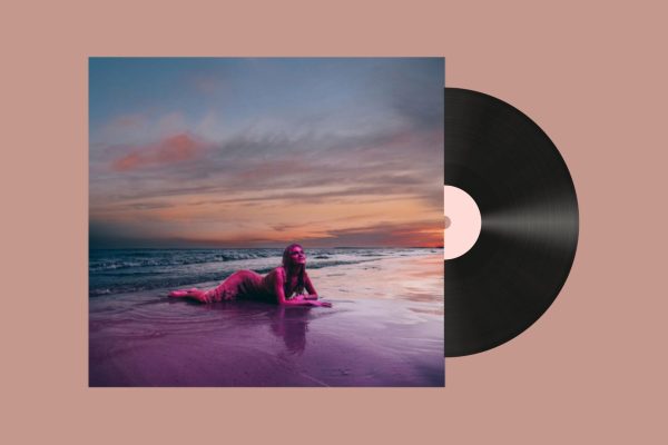 On a muted pink background is a square photograph of a woman lying on her stomach in the waves of a beach, staring up at the sunset sky. Behind the album, a record disc comes out.