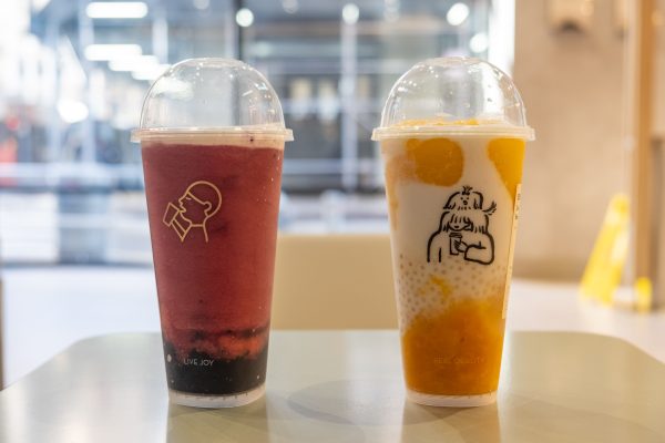 Two drinks side-by-side on a table. One is dark pink, and one is white and orange.