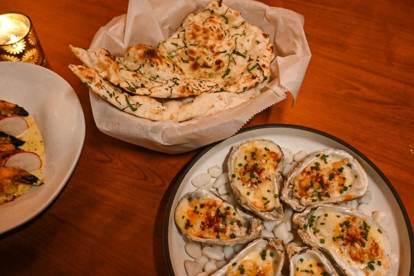 A plate of buttered naan topped with greens next to a plate of oysters