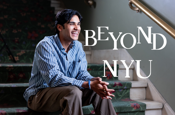 A close-up shot of a man wearing a blue-striped shirt and brown pants sitting in a floral-decorated staircase with big white words that say “BEYOND N.Y.U.”