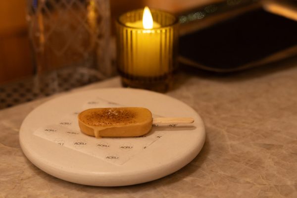 A yellow popsicle on a white plate.