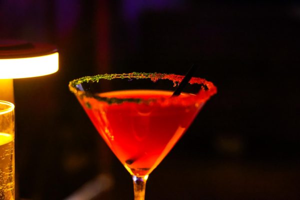 A red cocktail with red and green salt on the rim.