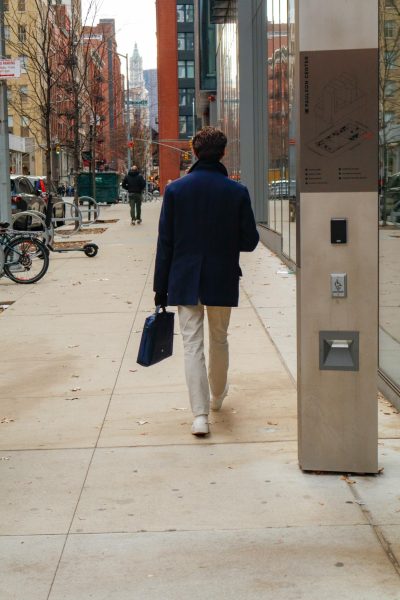 A man in a blue coat and khaki pants walking on the street.