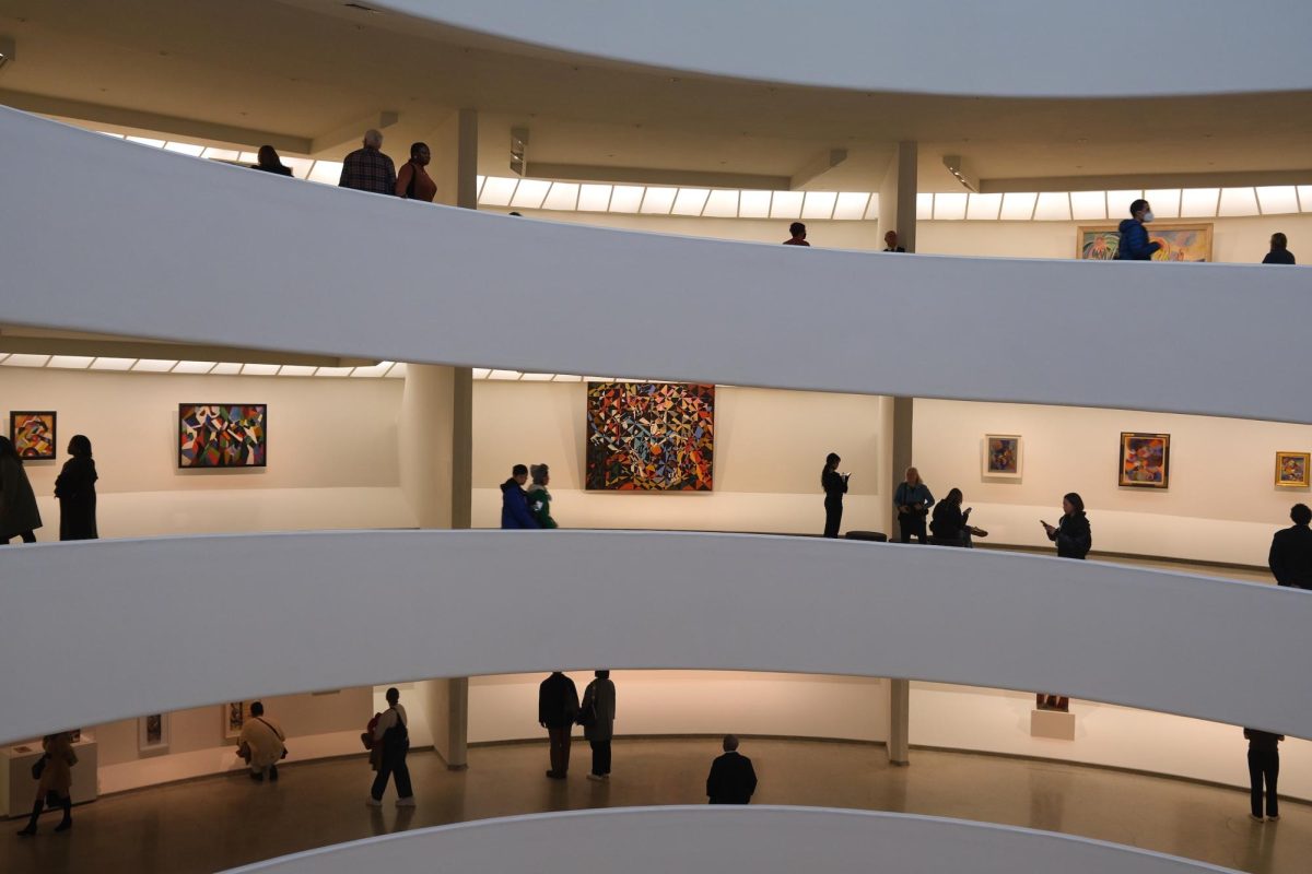 Three balconies spiraling up with various art pieces on the walls and people perusing them.