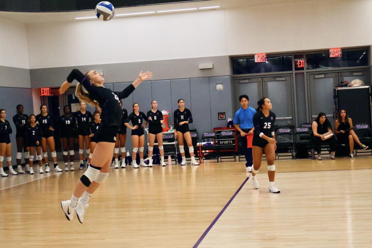 A student athlete is midair preparing to spike an incoming volleyball.