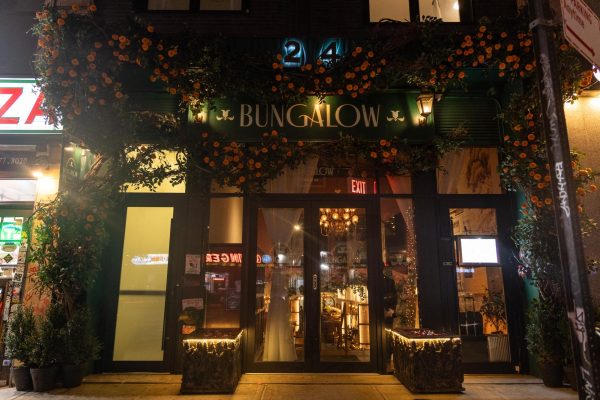 A green restaurant with orange flowers on vines and a sign that reads “BUNGALOW.”