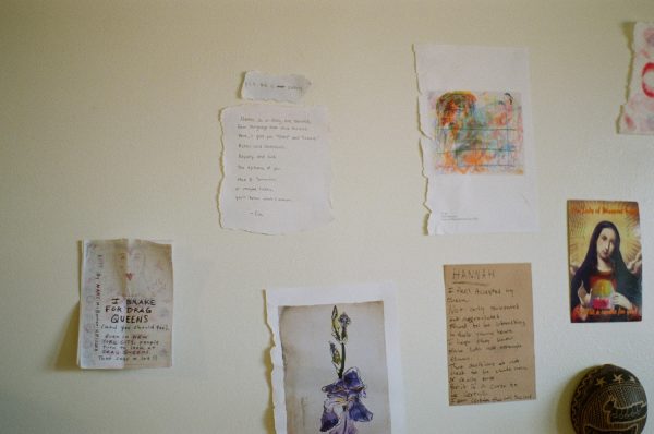 Art pieces and writing on paper taped onto a wall.