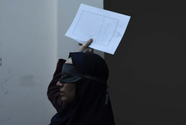 A woman wearing a blindfold holding a piece of paperwork over her head.