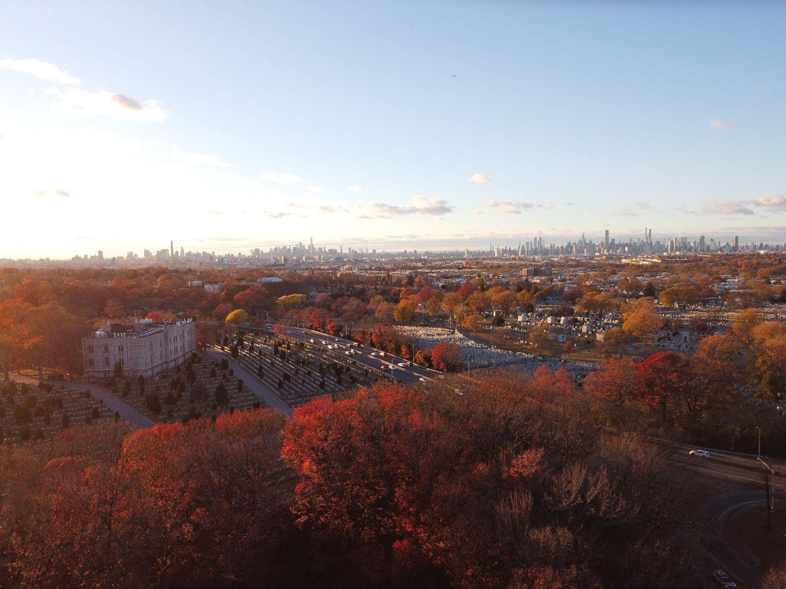 An aerial view of an autumn field with a runway and body of water, with factories and suburbs on the left.