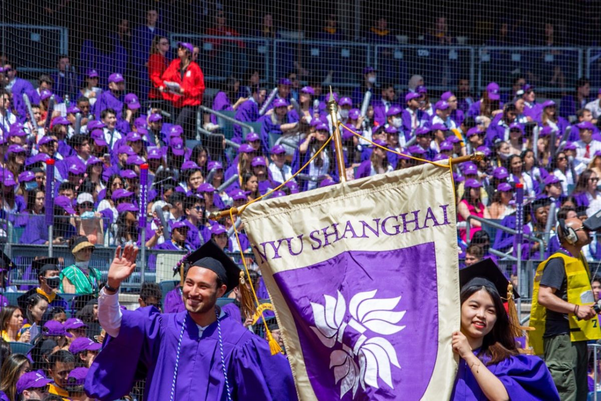 NYU graduates Matthew Fertig, left, and Mengjie Shen, right, carry the NYU Shanghai banner during the school procession. (Manasa Gudavalli for WSN)