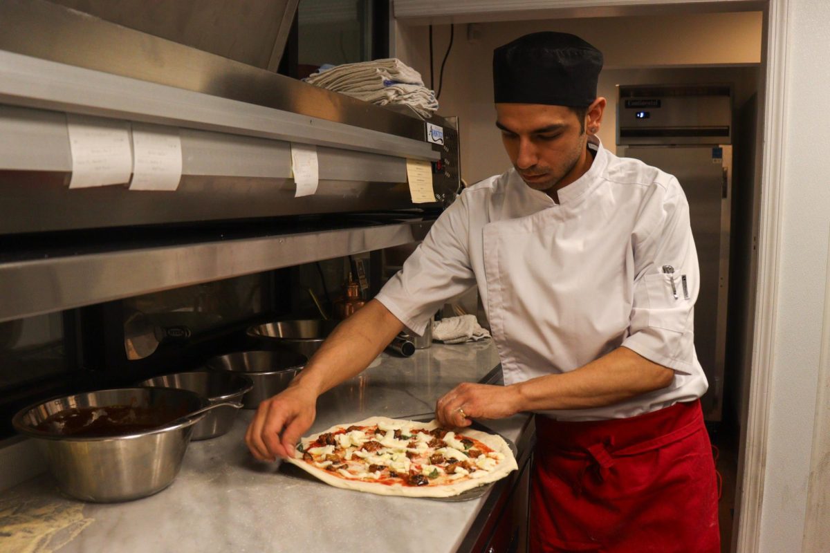 A chef at Moody Tongue Pizza prepares pizza for a table. (Ivy Chan for WSN)