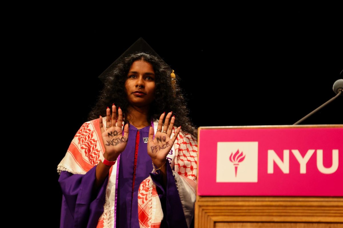 A Film and Television student receiving their symbolic diploma silently protests by raising their hands to reveal “NO JUSTICE” and “NO PEACE." (Julia Smerling for WSN)